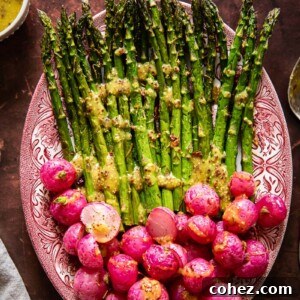 top down view on roasted asparagus and radishes with vinaigrette drizzled over.