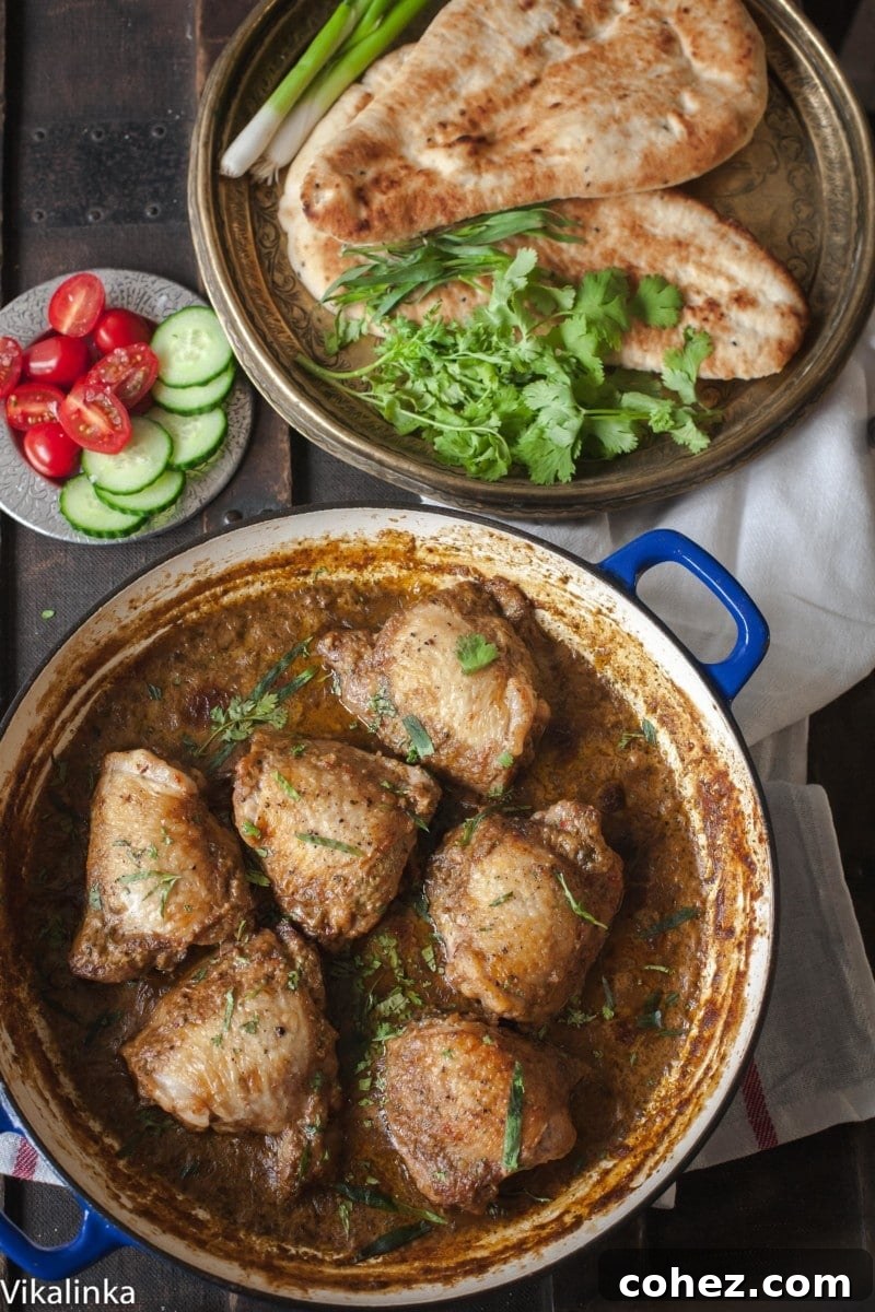 Top down view of chicken simmering in garlic walnut sauce in a cast iron pan