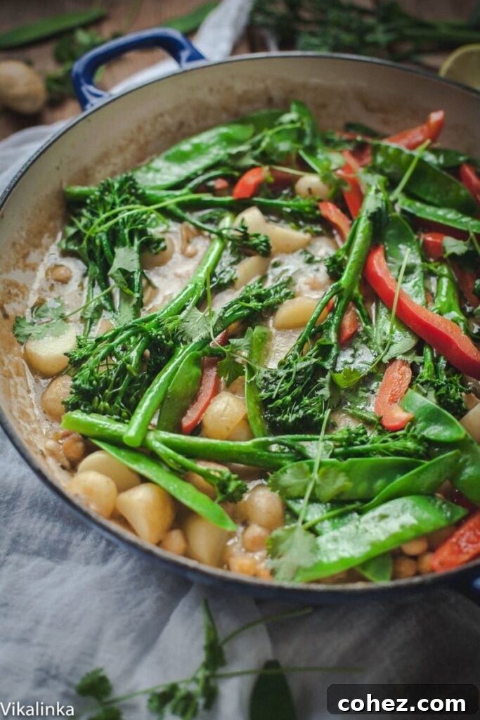 Vibrant Vegetarian Thai Green Curry with new potatoes, snow peas, chickpeas, and broccoli, served in a bowl.