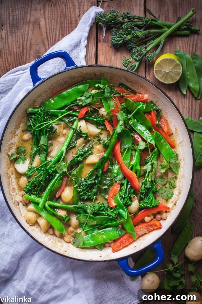 Close-up of a pot of Vegetarian Thai Green Curry simmering, showing green vegetables, young potatoes, and chickpeas.