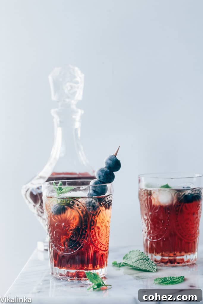 Two glasses of Vermouth Cassis, adorned with fresh mint and berries, glistening in the summer light.