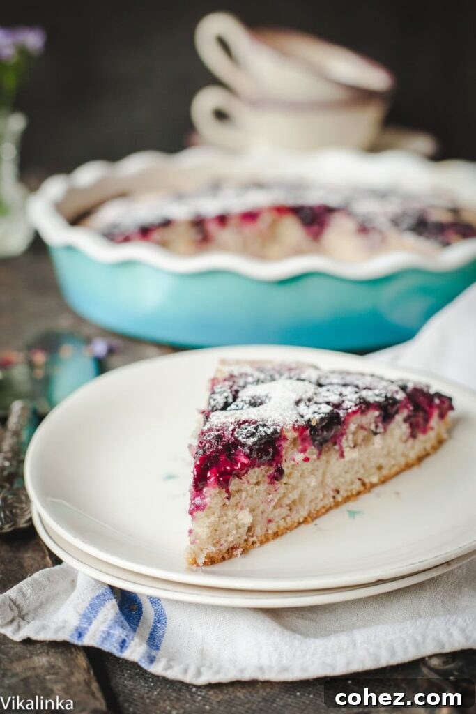 A close-up shot of a single slice of homemade Wild Blackberry Tea Cake on a delicate plate, showcasing its soft crumb and juicy, burst blackberries.