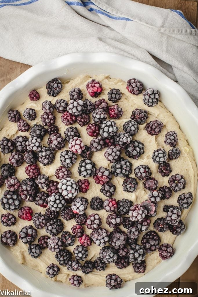 Unbaked Wild Blackberry Tea Cake batter in a baking dish, generously topped with a layer of fresh blackberries, poised for the oven.