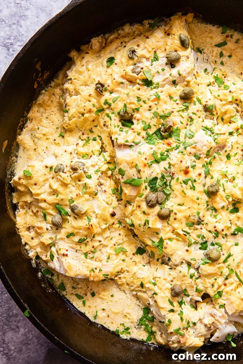Golden Baked Cod with Zesty Mustard Sauce 2 Perfectly baked cod with a creamy, golden mustard sauce, garnished with fresh herbs, presented in a rustic black skillet