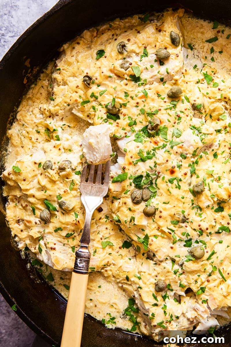 Golden Baked Cod with Zesty Mustard Sauce 6 A beautifully presented baked fish, generously covered in a creamy sauce and sprinkled with vibrant fresh chopped parsley, served in an elegant cast iron skillet
