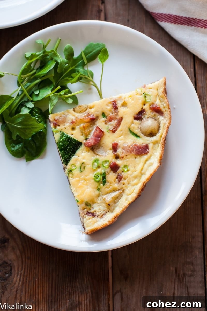 Loaded French Omelette with Bacon, Potatoes and Zucchini 4 A perfectly cooked slice of French omelette with a fresh side salad on a pristine white plate