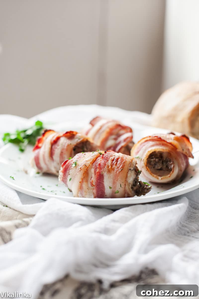 Close-up of three bacon wrapped chicken thighs on a plate, highlighting the delicious filling visible at the ends and the texture of the bacon