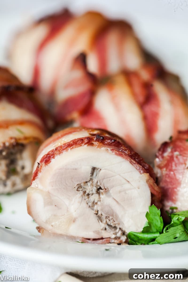 Close-up of a cross-section of a bacon wrapped chicken thigh, showcasing the juicy chicken, crispy bacon, and creamy filling in detail