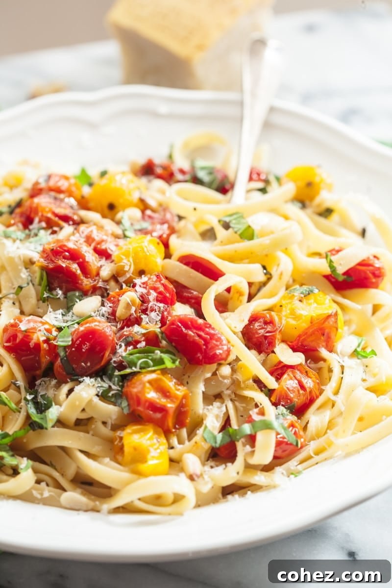 A serving of fettuccine pasta generously coated with roasted cherry tomato and basil sauce, ready to be garnished.