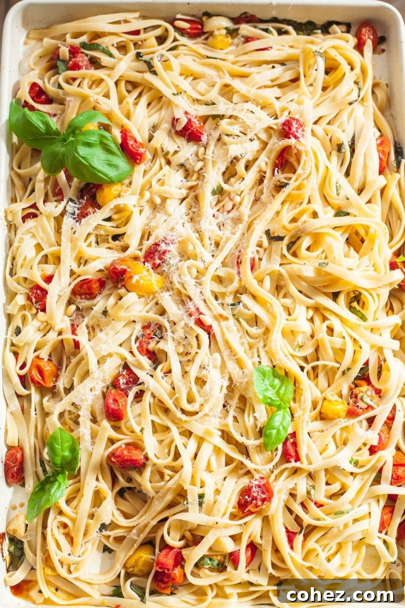 Tagliatelle pasta generously tossed with roasted cherry tomato and basil sauce directly in a rectangular roasting pan.