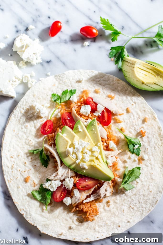An open Peri Peri Rice and Chicken Wrap on a rustic table, garnished with fresh avocado slices and a dollop of spicy yogurt sauce