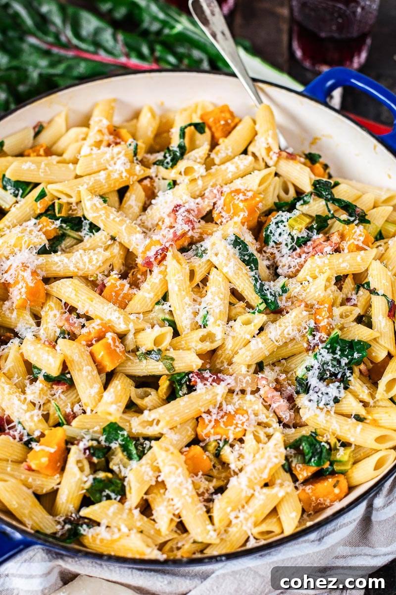 Penne pasta with golden roasted squash, crispy pancetta, and fresh Swiss chard, served in a rustic bowl, highlighting its vibrant colors and inviting textures.