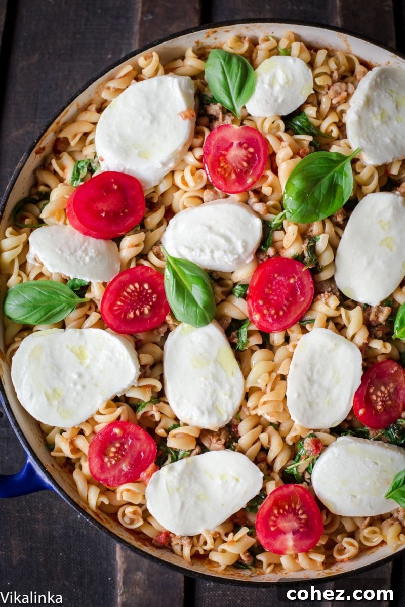 Top-down view of baked fusilli with sausage, fresh arugula, and melted mozzarella, ready to serve