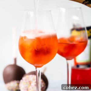 Bottle of sparkling wine pouring into a glass with orange drink