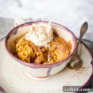 Side shot of Spiced pumpkin cake in a mug with cream on top
