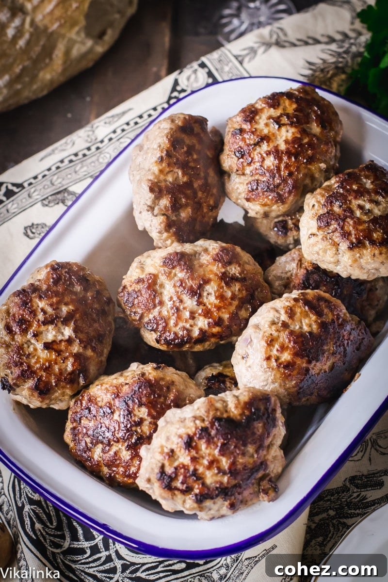 A pristine white enamel dish brimming with perfectly cooked, golden-brown Russian meat patties, hinting at the rich flavors within.