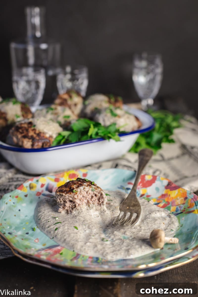 A single beef patty, beautifully presented on a vibrant blue plate, generously covered with a rich and creamy mushroom sauce, ready to be enjoyed.