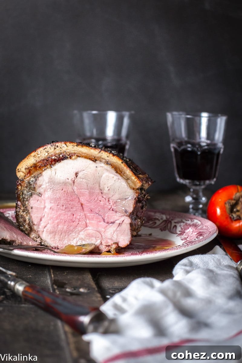 Beautifully carved pork roast presented on a serving board, accompanied by two glasses of red wine, ready for a festive meal.