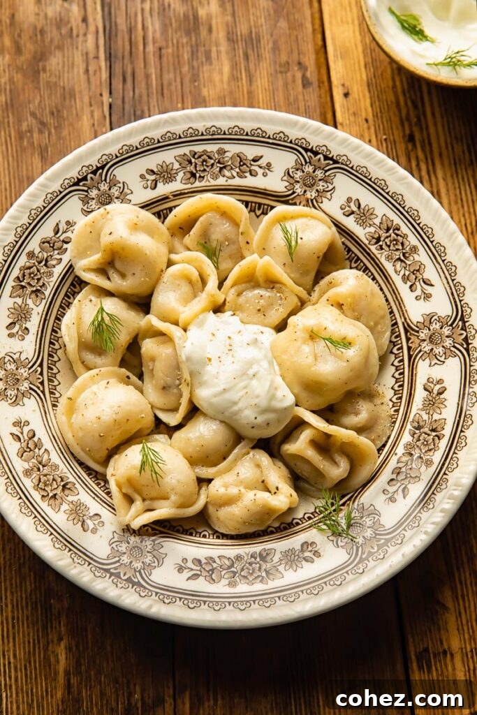 Classic Siberian Pelmeni 5 top down view of a large bowl with dumplings and a dollop of sour cream