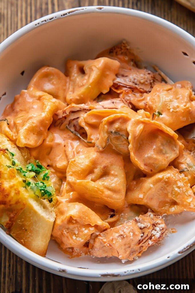 bowl of tortellini in cream sauce with piece of garlic bread