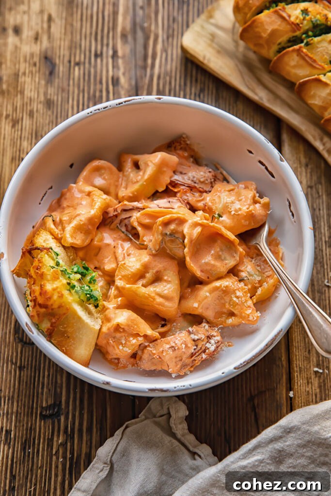 bowl of tortellini with a fork and garlic bread