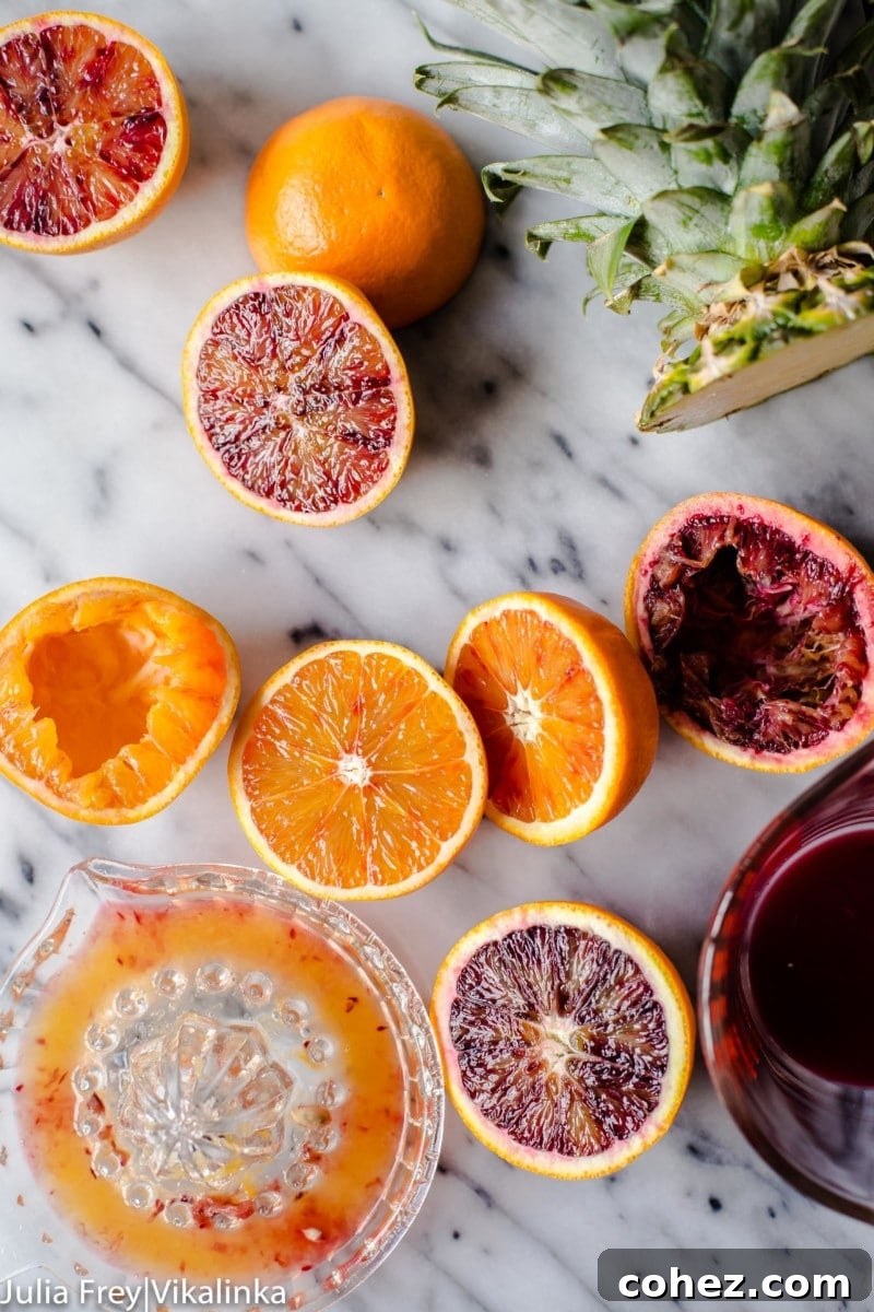 orange and blood oranges cut in half, a juice and a cut pineapple