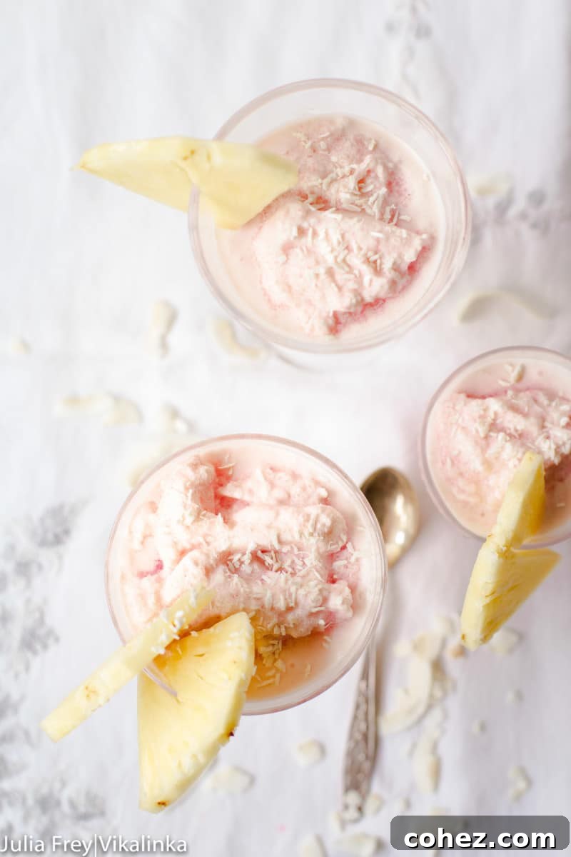 Top-down view of three glasses filled with Frozen Blood Orange Pina Colada, garnished