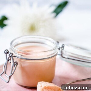 A close-up of smooth, luscious rhubarb curd in a glass jar, highlighting its creamy texture and rich color.