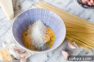 Bowl with cheese and eggs beside spaghetti