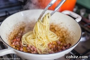 Effortless Cream-Free Carbonara Sauce 11 Tongs adding pasta to bacon