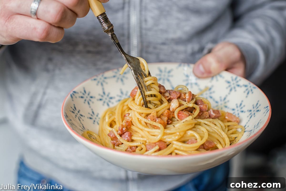 Effortless Cream-Free Carbonara Sauce 3 Hand holding pasta bowl