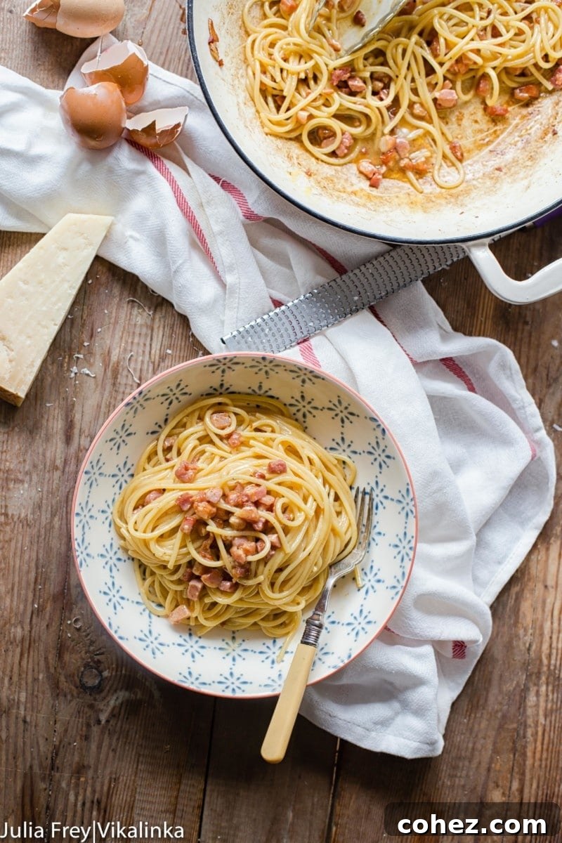 A top-down view of spaghetti carbonara in a serving bowl, with a pot of cooked pasta in the background, illustrating the simplicity and rustic charm of the dish.
