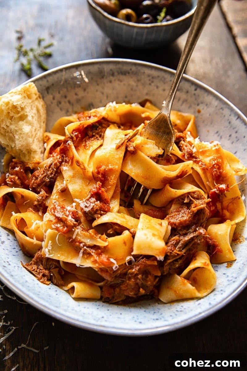 A comforting bowl of Rustic Italian Beef Ragu, served with a piece of crusty bread and a fork, highlighting its rich texture and vibrant color.