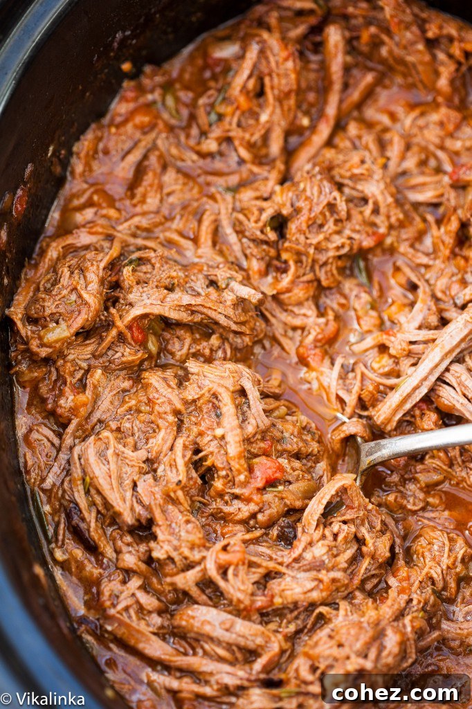 A close-up view of chunky, slow-cooked beef ragu simmering in a pot, showcasing its rich texture and deep color.