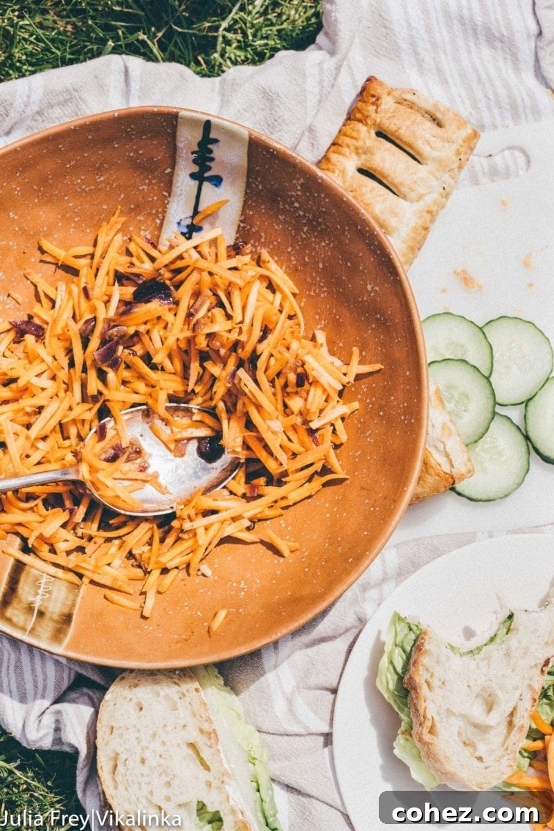 An inviting picnic spread, featuring Korean Carrot Salad alongside sandwiches and fresh cucumbers, perfect for outdoor dining.