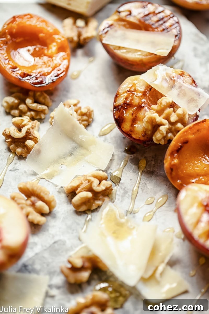 Close up of peaches and apricots along with cheese shavings, honey and walnuts