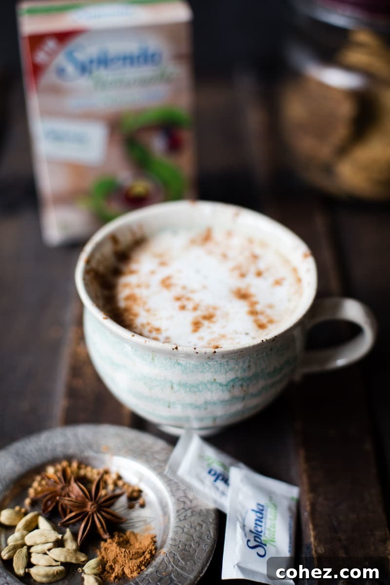 Overhead shot of two glasses of spiced chai latte, garnished with frothed milk and a cinnamon stick, ready for serving.