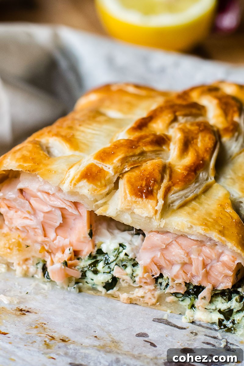Regal Salmon in Golden Crust 4 A close-up view of a baked Salmon en Croute, sliced to reveal the perfectly cooked salmon and the vibrant green mascarpone and kale filling.
