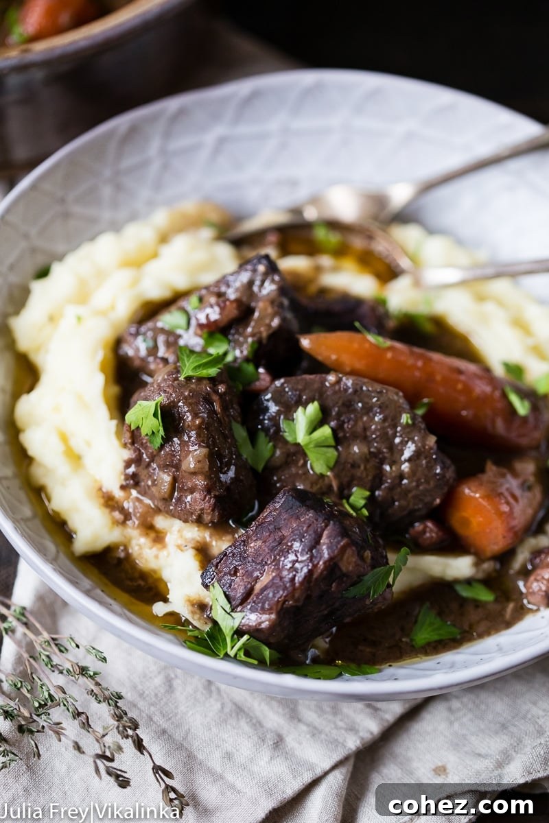 A close-up shot of Beef Bourguignon in a bowl, generously portioned over mashed potatoes