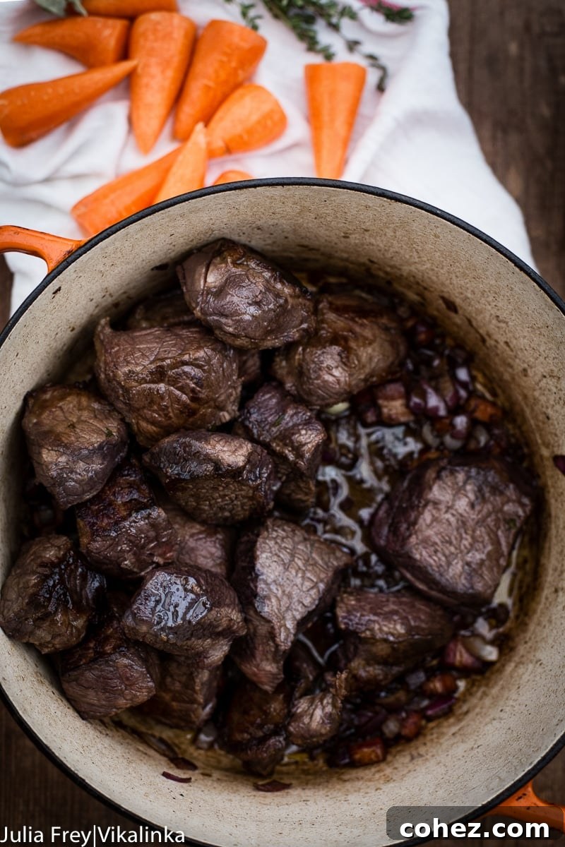 Beef Bourguignon gently stewing in a heavy cast iron pot on the stovetop