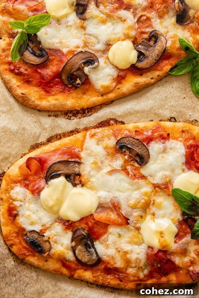 Naan pizza on baking sheet with mushrooms and cheese, ready for the oven