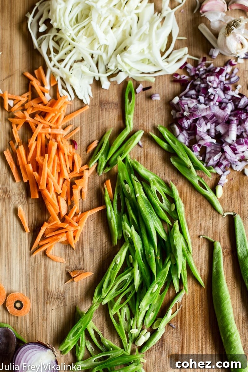 Fresh ingredients for Pancit Canton, including carrots, green beans, cabbage, and aromatics, ready for preparation.