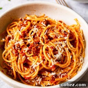 spaghetti bolognese sprinkled with Parmesan in cream bowl