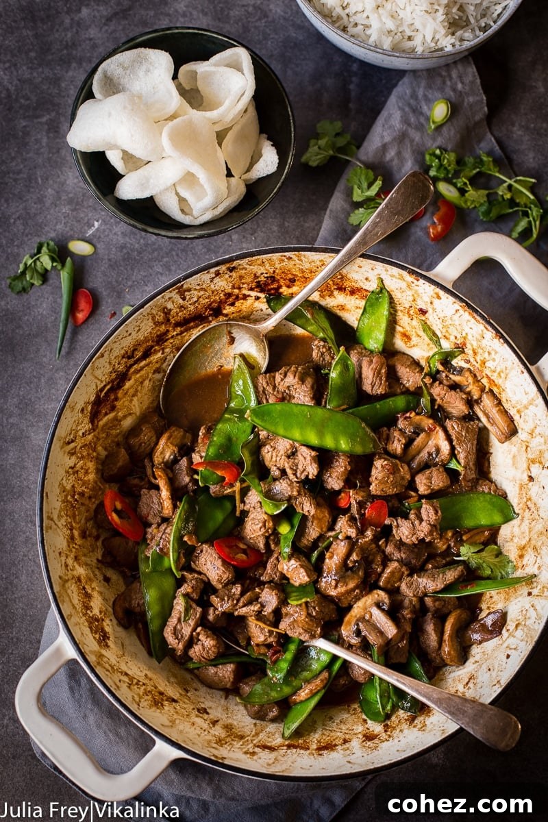 Top-down view of a complete meal featuring Beef, Mushroom and Snow Pea Stir Fry, fluffy white rice, and crispy prawn crackers.