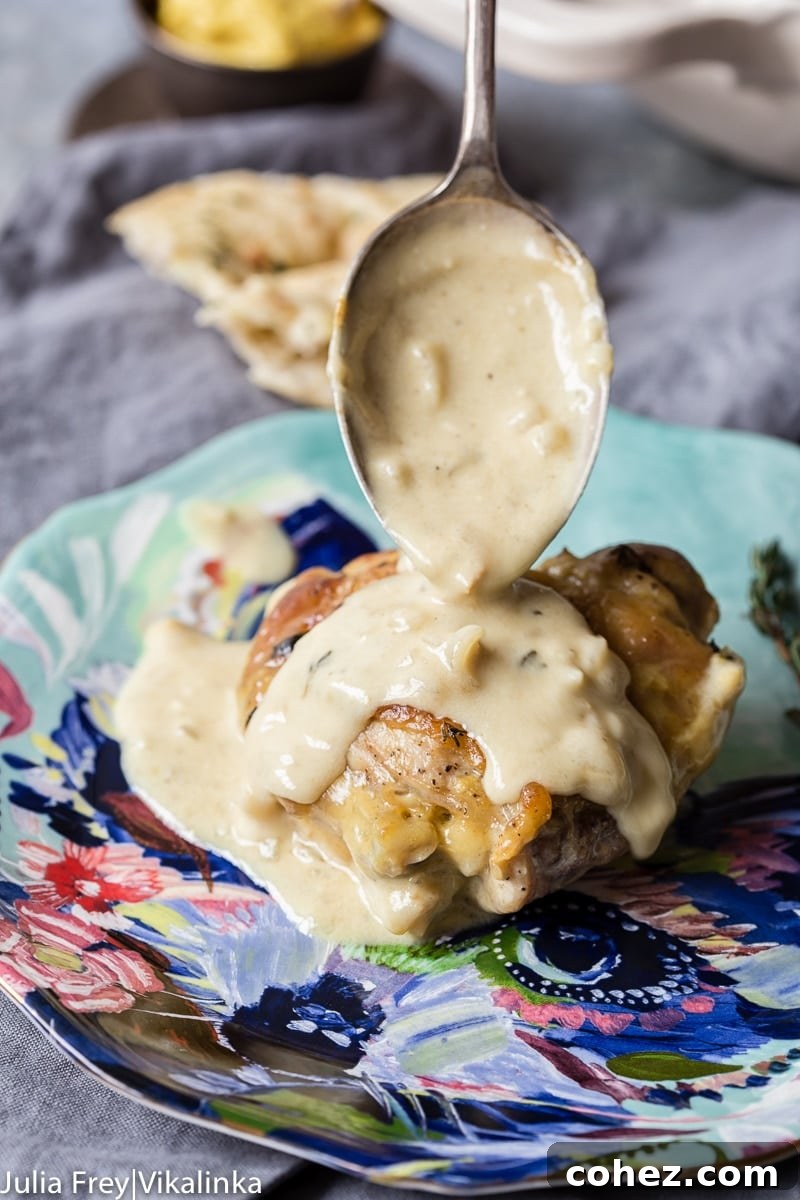 Gourmet Wine and Mustard Chicken 3 A piece of braised chicken being spooned with rich, creamy mustard sauce on a white plate