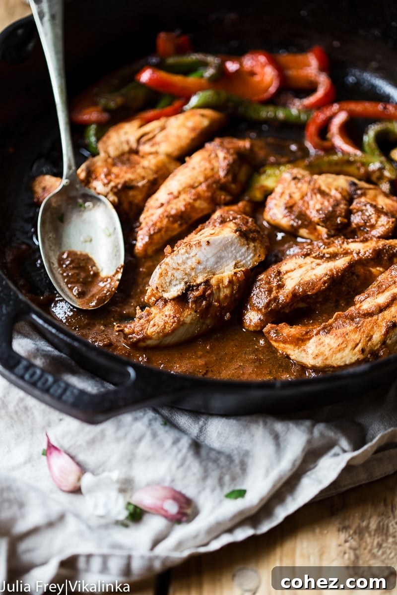 Sizzling chicken and bell peppers cooking in a cast iron pan, forming the heart of a delicious fajita bowl.