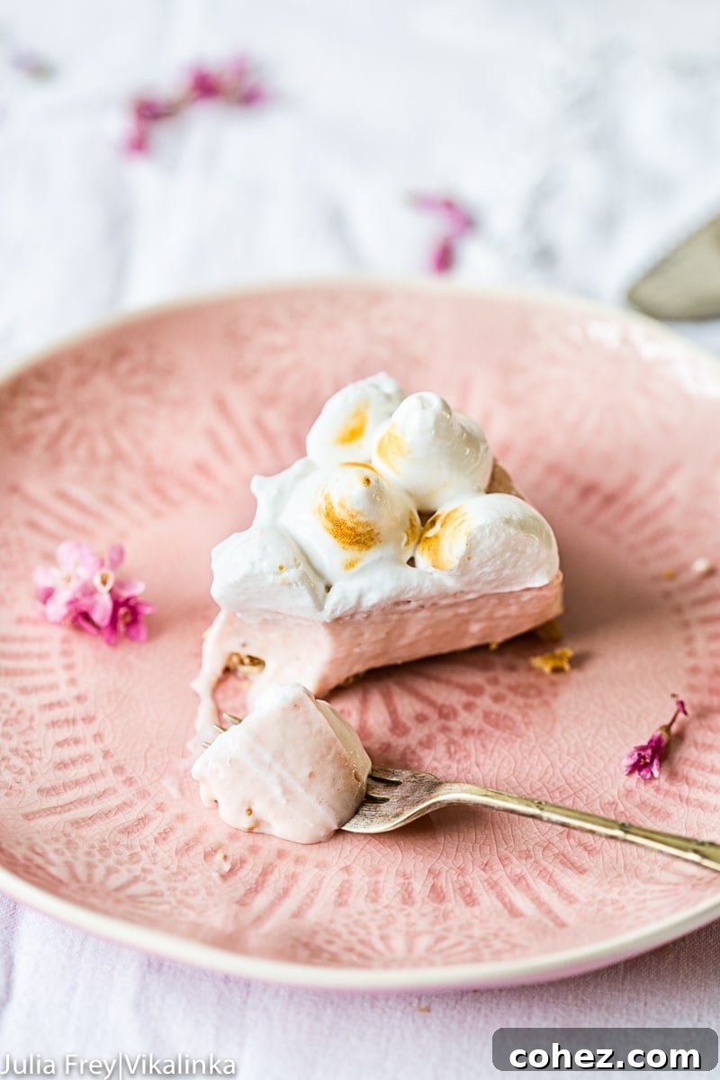 Airy Strawberry Meringue No Bake Cheesecake 3 Piece of strawberry meringue cheesecake, partially eaten, with a fork showcasing its layers