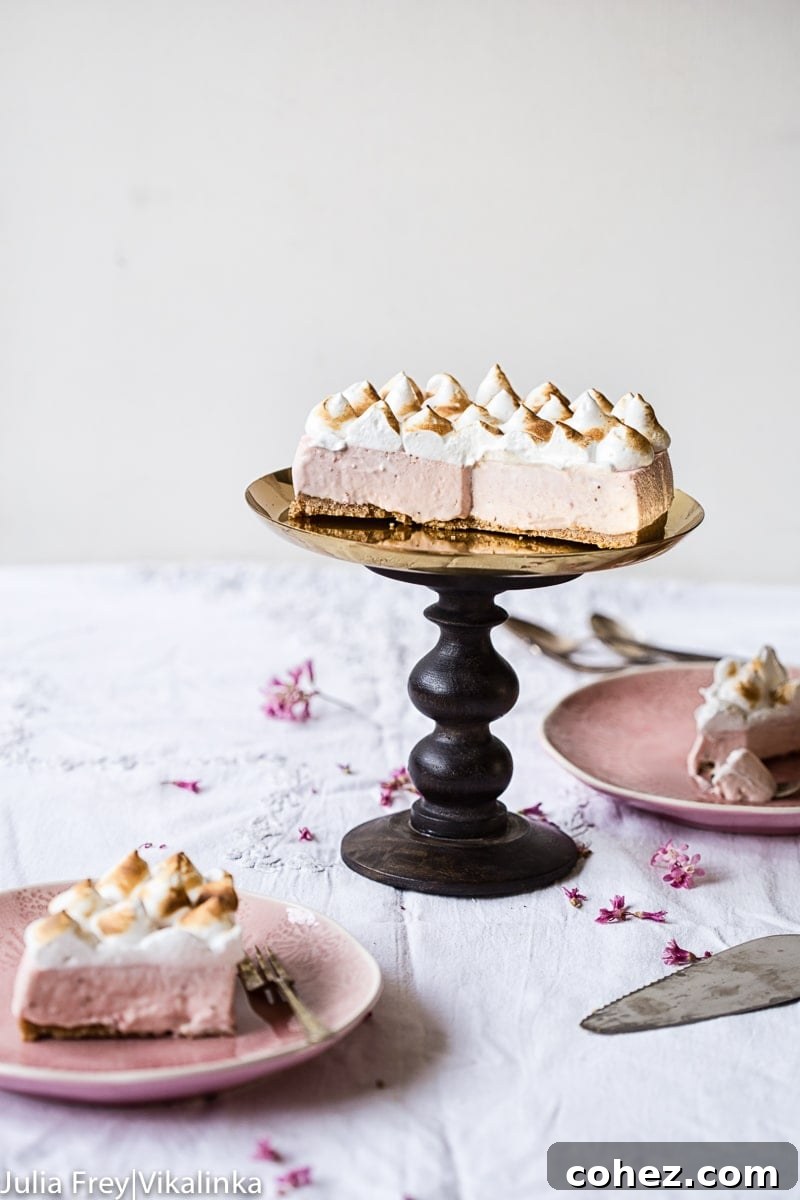 Airy Strawberry Meringue No Bake Cheesecake 6 Full strawberry meringue cheesecake on a cake stand with several slices removed and presented on plates