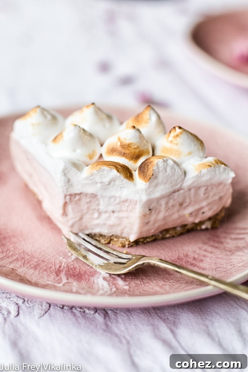 Airy Strawberry Meringue No Bake Cheesecake 7 Slice of strawberry meringue cheesecake with a fork removing a bite, highlighting its creamy texture