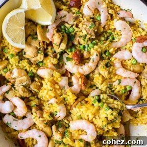 Top-down view of vibrant yellow Spanish rice with chicken, shrimp, and fresh lemon slices.